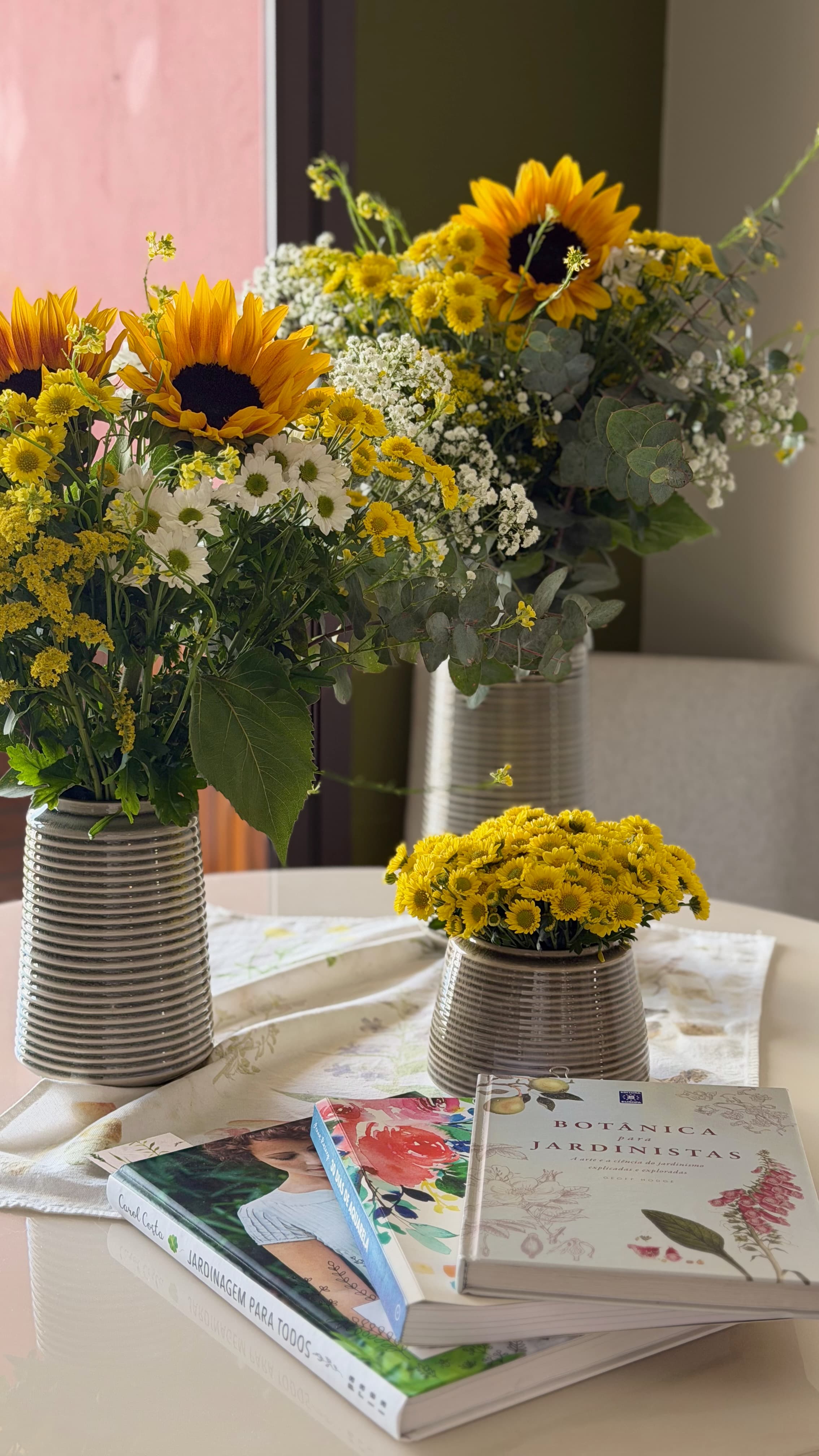 Composições florais amarelas em vasos sobre uma mesa com livros de botânica